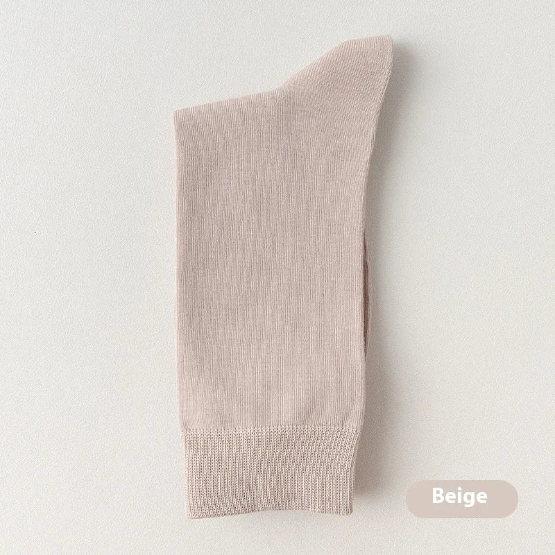 Pack of men's solid colour mid-calf business socks in combed cotton on a neutral background.