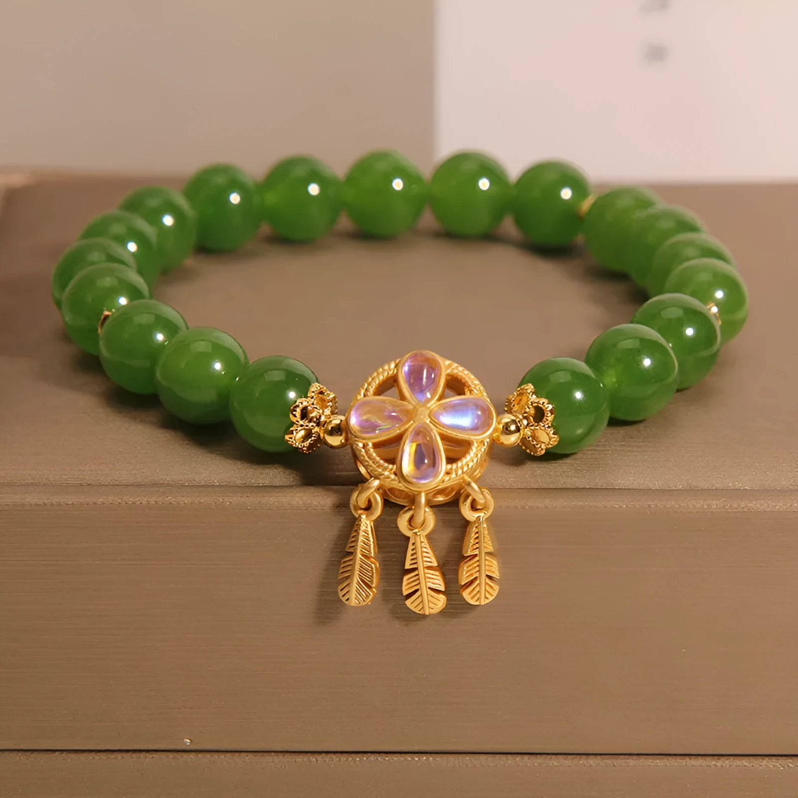 Women's green jasper crystal bracelet with four-leaf clover and dream catcher pendant, original design, on white background