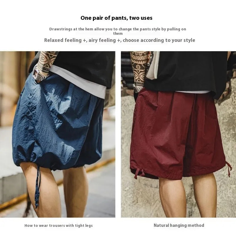 Men's loose Prussian Blue nylon shorts with embroidery on a beach background.