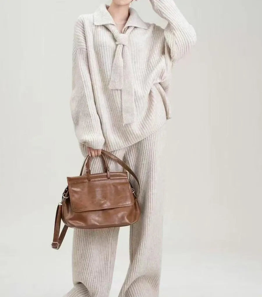 Dark gray knitted sweater and trousers two-piece set laid flat, showing long sleeves and elegant stitching details.