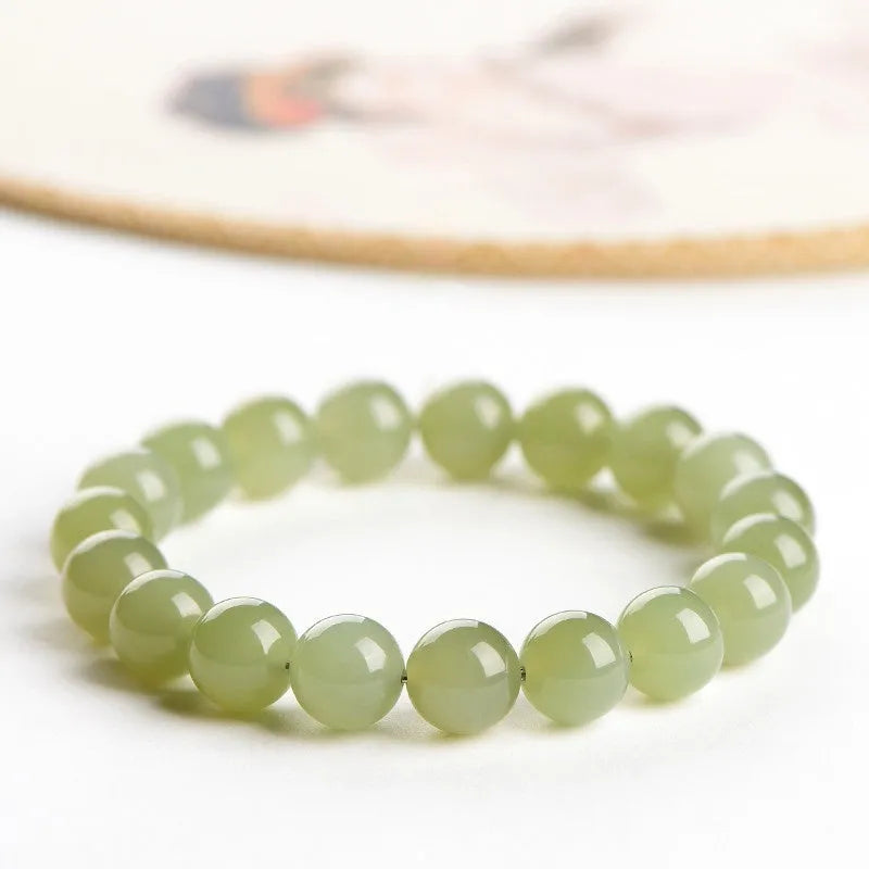 Polished Hetian jade ball bracelet in clear water colour on a wrist, showing spherical beads.
