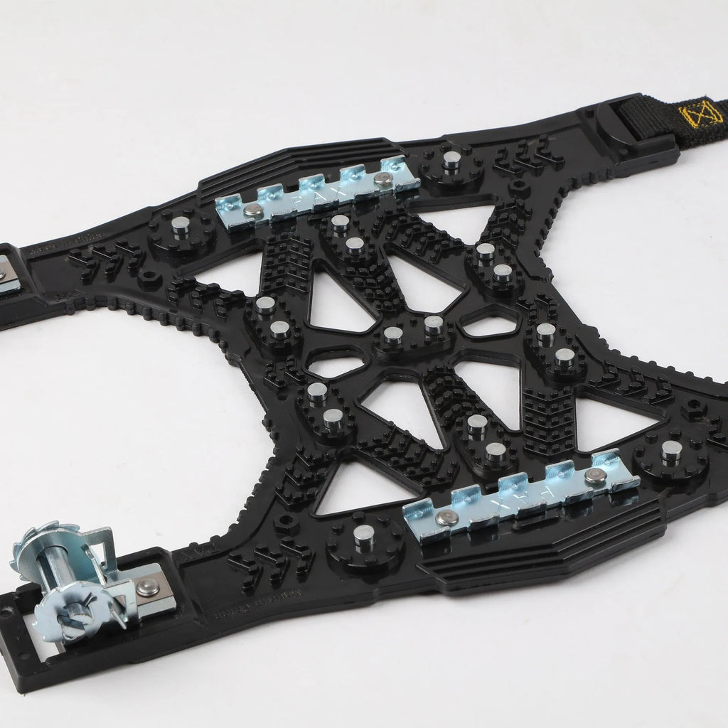 Universal nonskid chain with steel plate gear on a snowy road, black colour, with packaging on a table