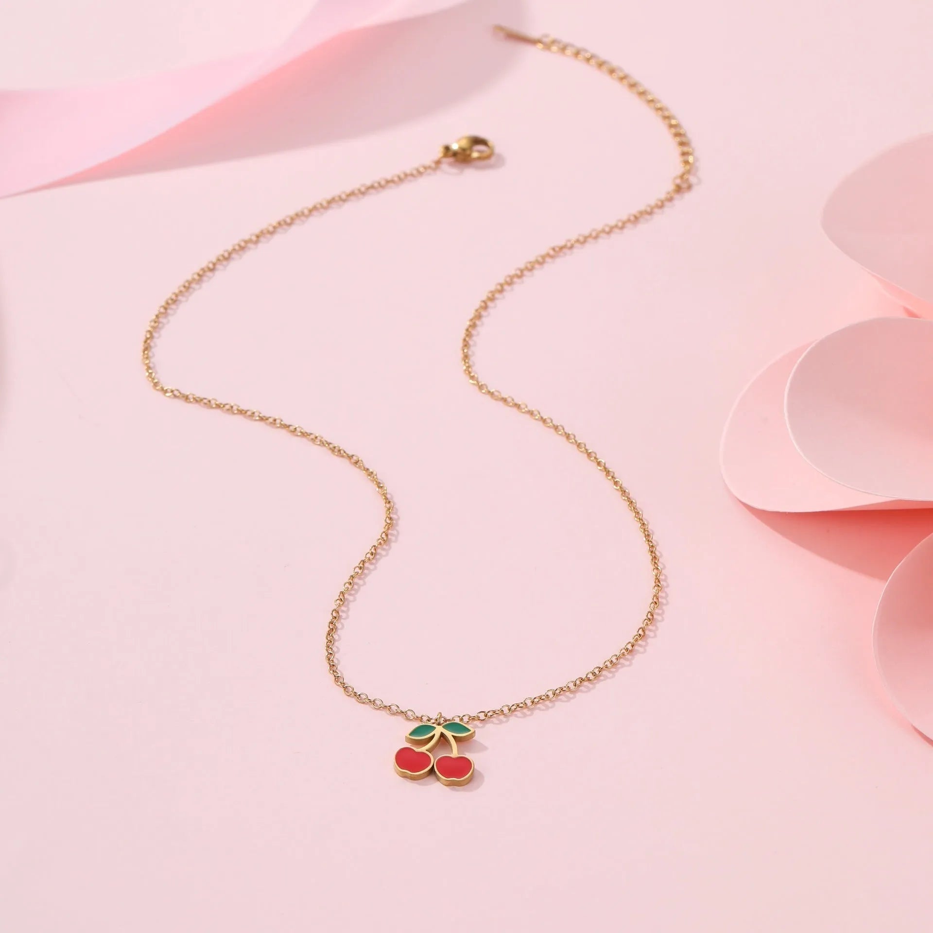 Four-piece cherry-themed jewellery set with gold electroplated necklace, bracelet, earrings, and ring on a white background.