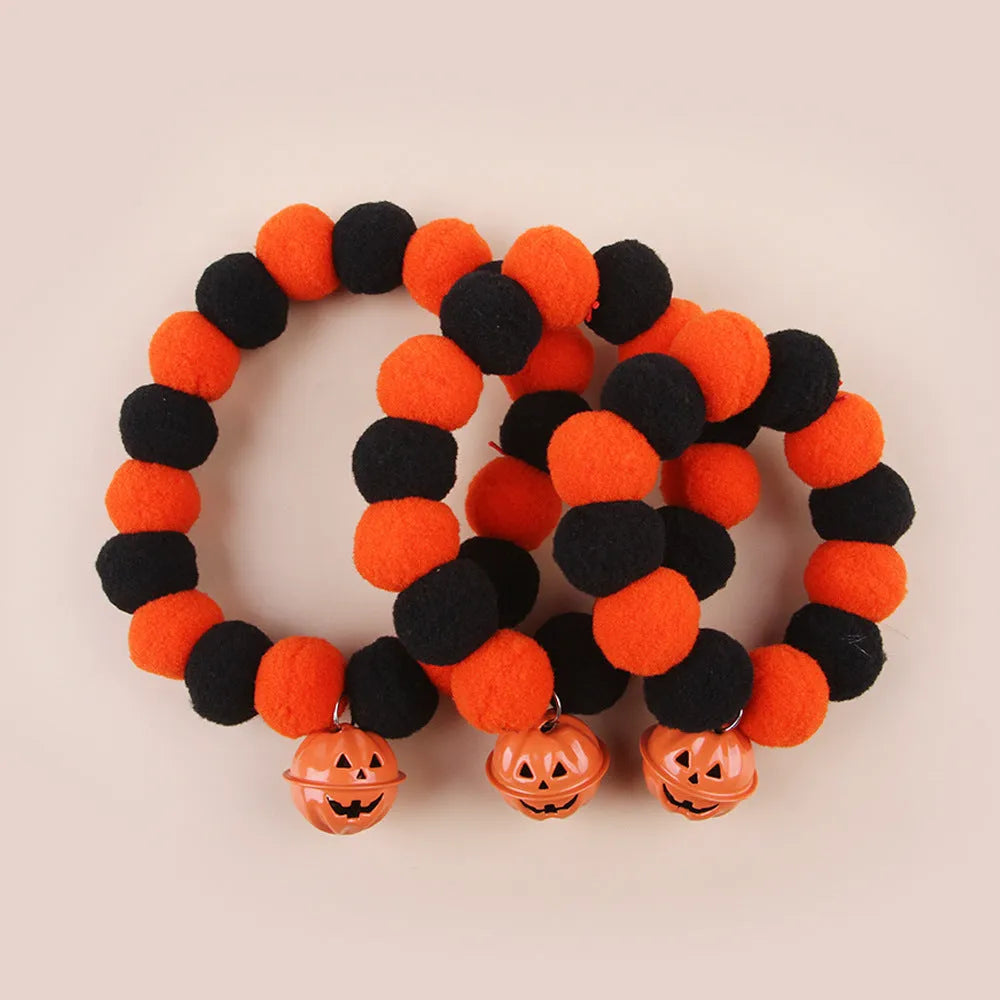 Orange Halloween pumpkin dog cat collar with green ribbon leaf, black stripes, jingle bell, and breakaway buckle on grey background.