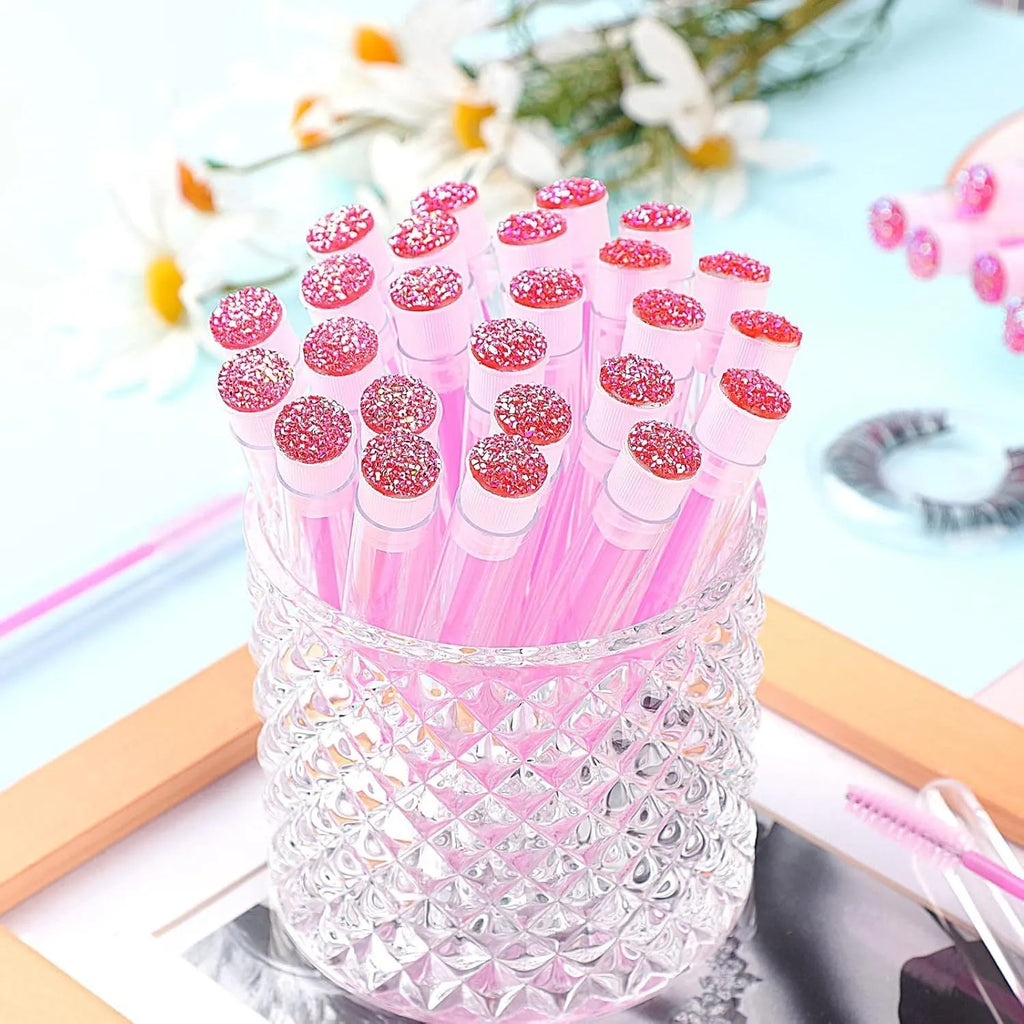 Disposable spiral mascara brushes in blue, green, pink, and purple with transparent storage tubes on white background