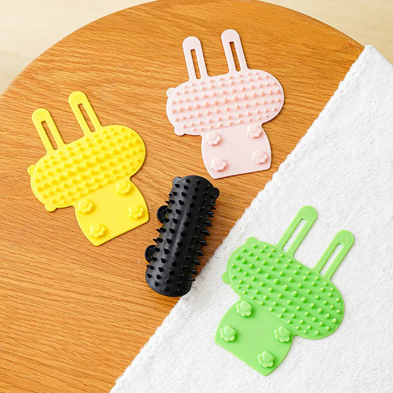 Silicone cat grooming comb with adjustable strap mounted on a table leg