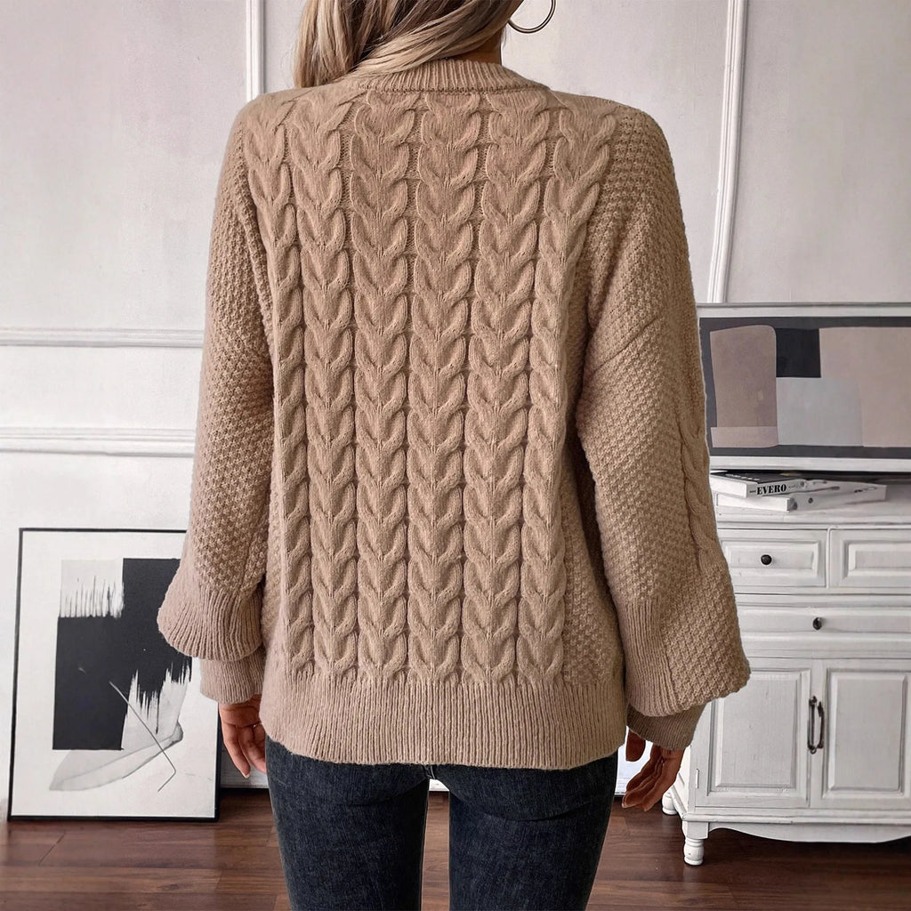 Women's loose beige pullover sweater with a twist detail and round neck on a hanger.