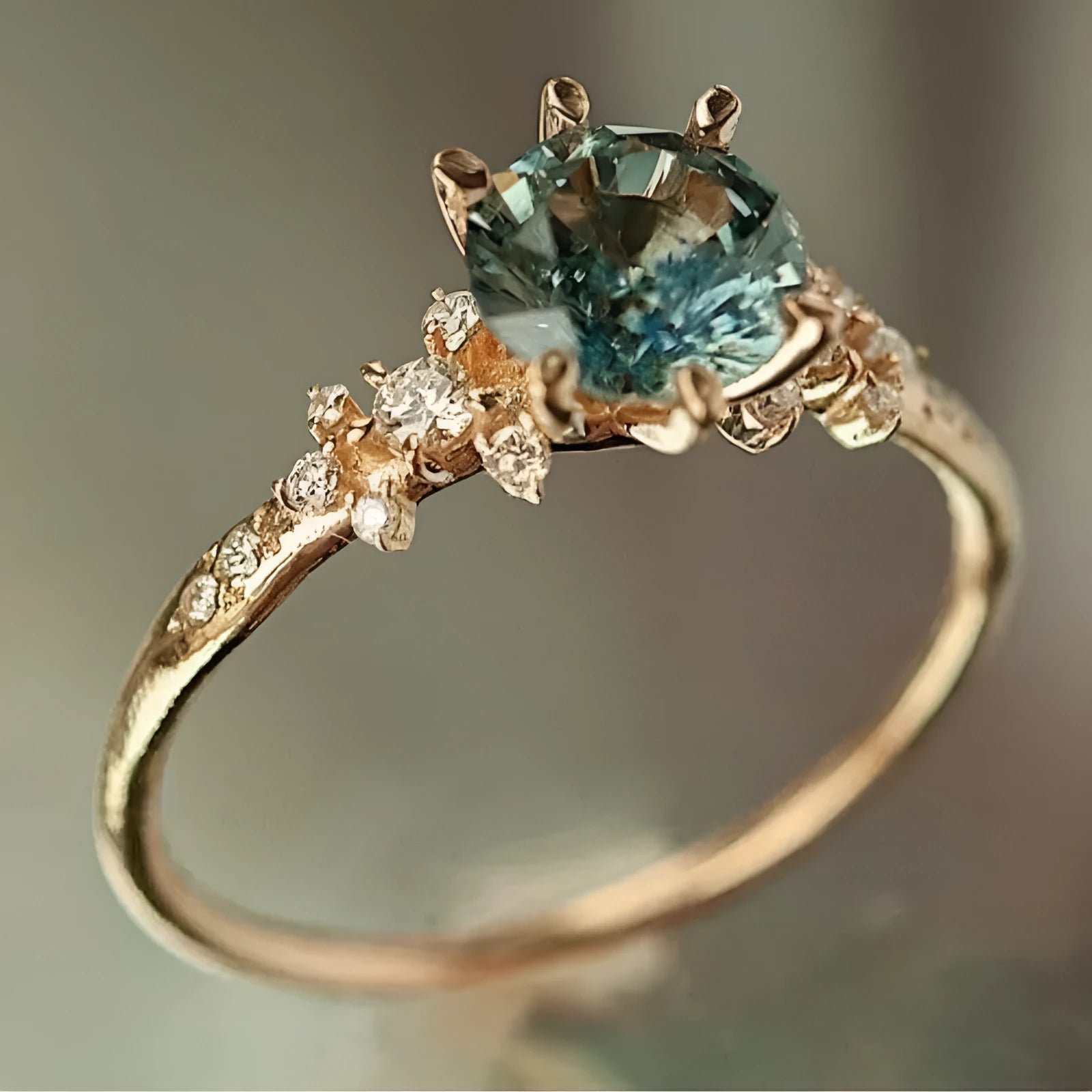 A gold-coloured geometric ring with a claw-set zircon stone and a chamfered square pattern on the band.