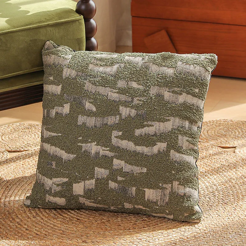 Square jacquard cushion cover with woven floral pattern on a grey sofa, showing zip closure and textured fabric.