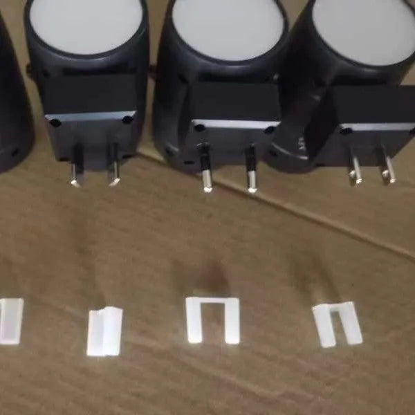Small white plug-in night lamp with rotatable head showing adjustable brightness control, plugged into wall socket