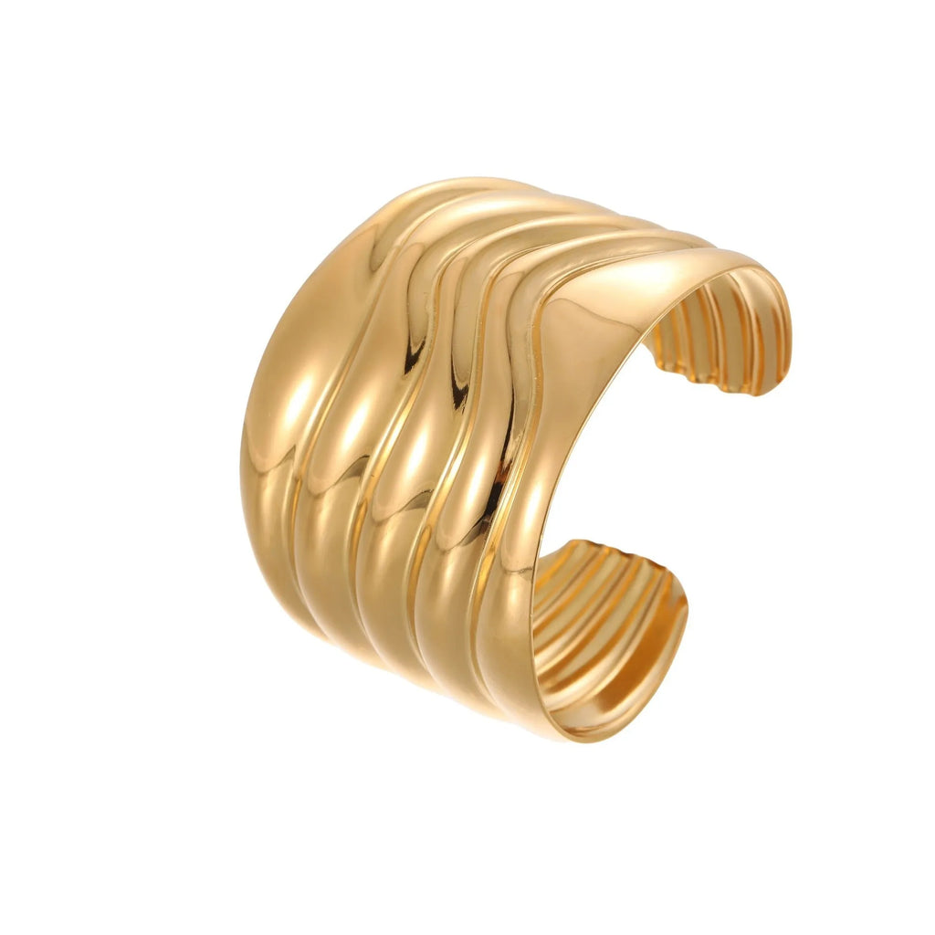 Wide geometric wave bracelet in gold-plated stainless steel on a woman's wrist.