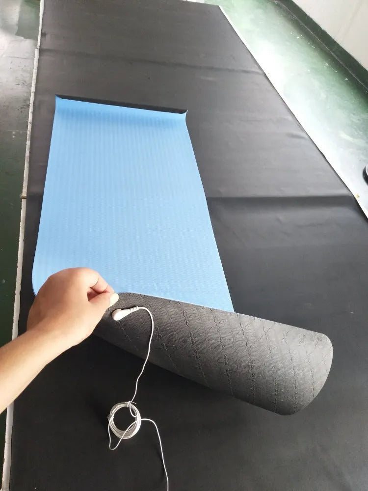 Blue yoga mat with plants pattern and a black grounding wire attached.