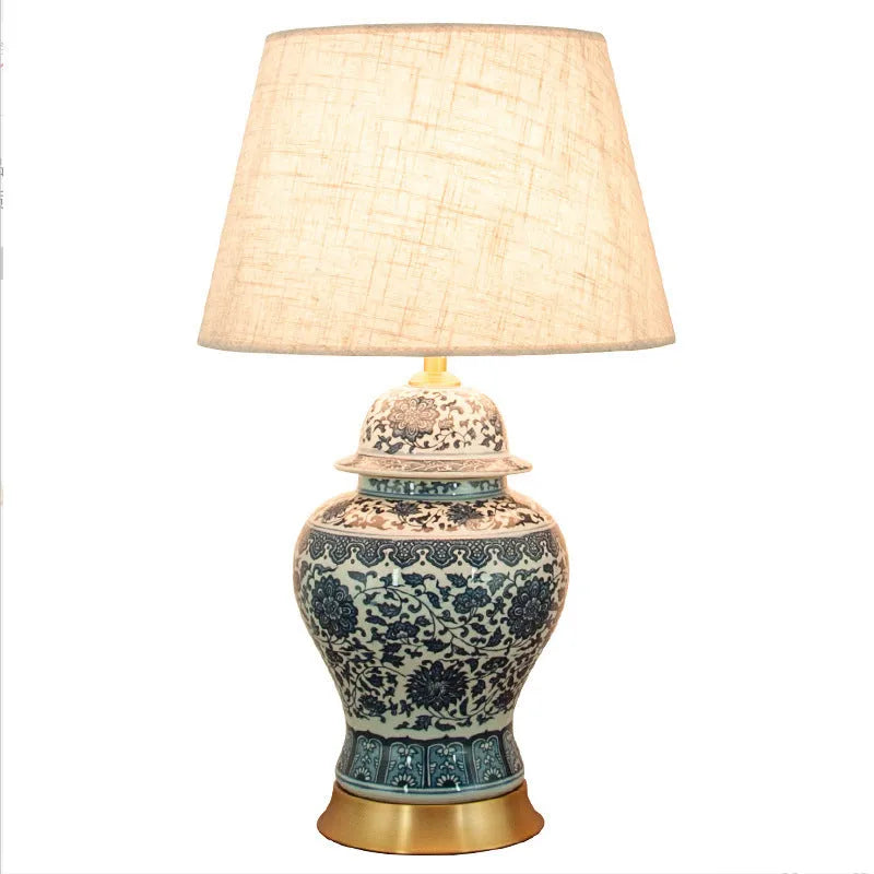 Blue and white porcelain Chinese table lamp with copper base and cloth shade on bedside table