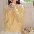 Women's cardigan sweater with a decorative bow and pearl buttons, shown in a solid colour.