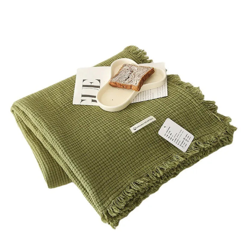 Cotton four-layer gauze throw blanket with tassel edges shown in avocado green colour.