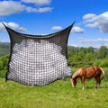 Woven PE rope horse feeding bag with grid pattern in black colour, shown hanging with hay
