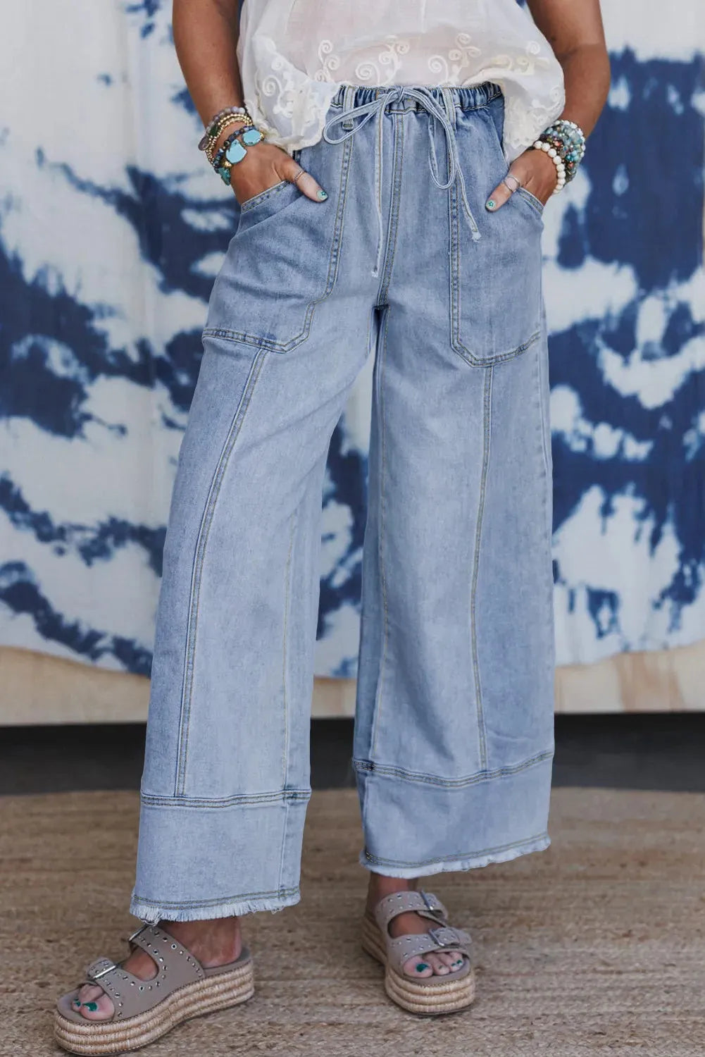 Beau Blue wide leg denim trousers with drawstring waist and raw hem finish laid flat