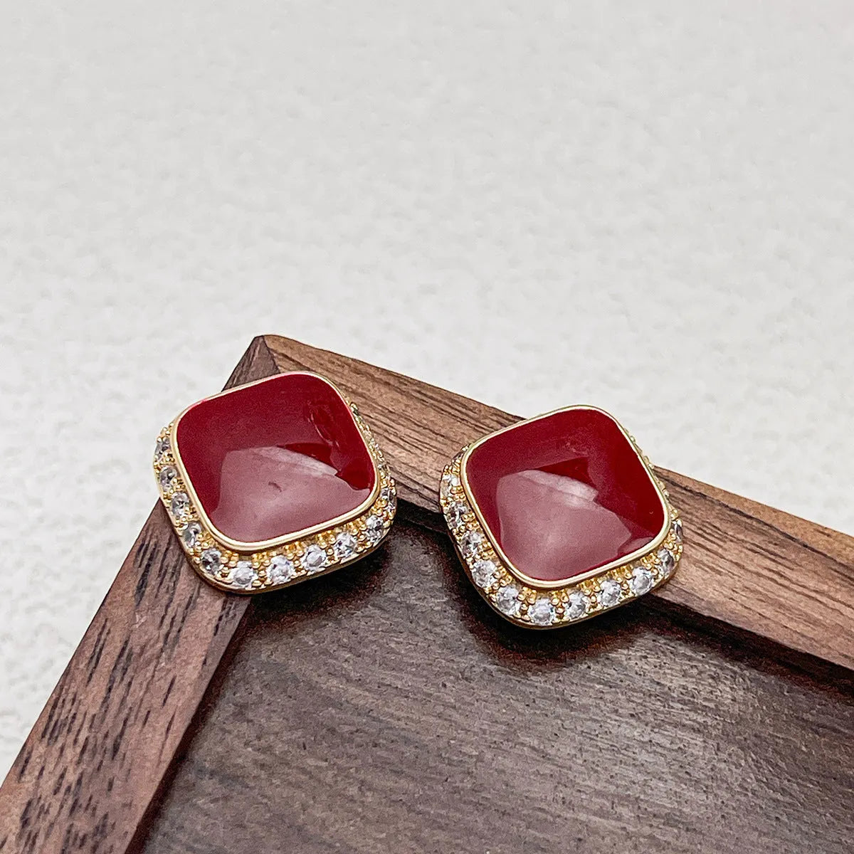 A pair of red geometric square alloy earrings with inlaid detailing on a white background.