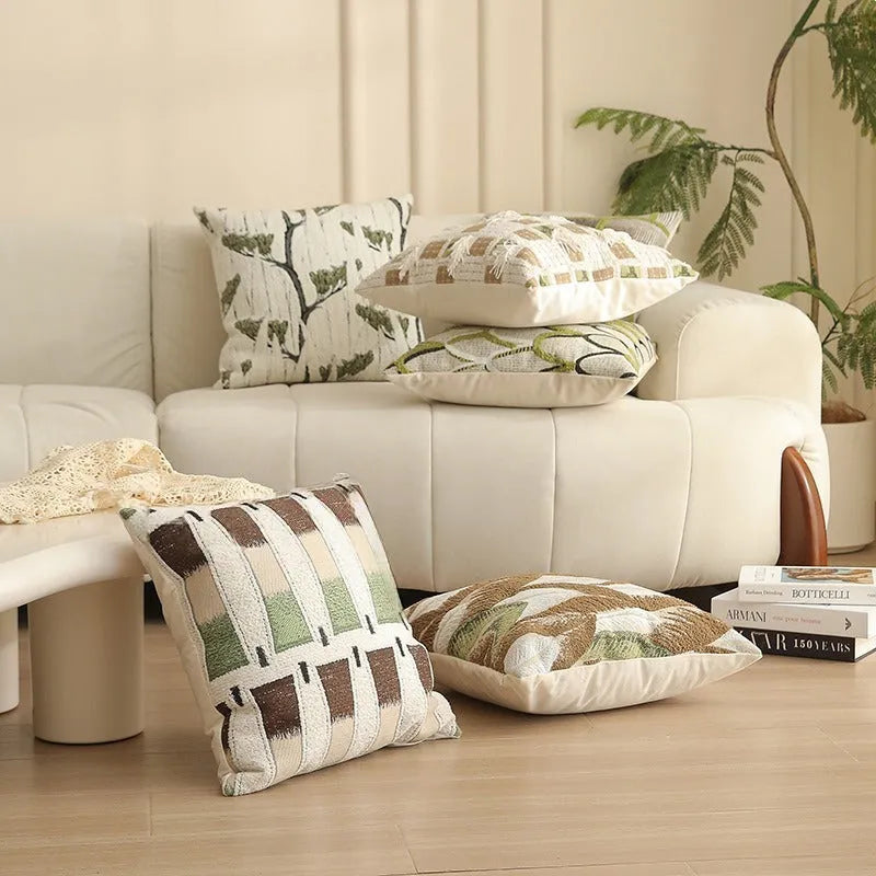 Square jacquard cushion cover with woven floral pattern on a grey sofa, showing zip closure and textured fabric.