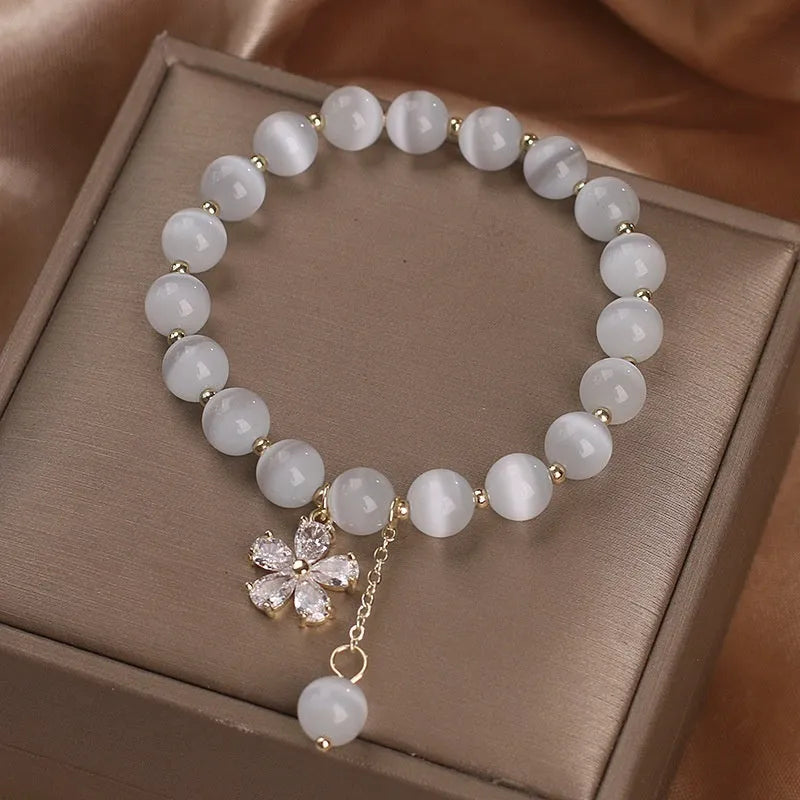 Women's white cat's eye crystal bracelet with flower decoration, tassel detail, and morganite safety buckle pendant