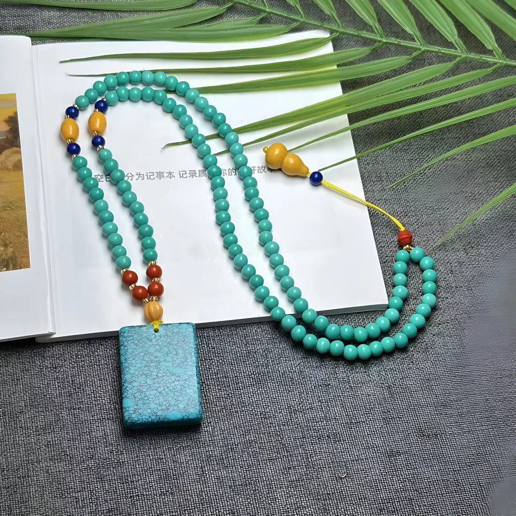 Turquoise stone pendant necklace with hand-woven mesh flower design on adjustable ball bead chain