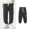 Men's loose-fit tapered cotton trousers in grey, showing the mid-waist and tapered leg cut.