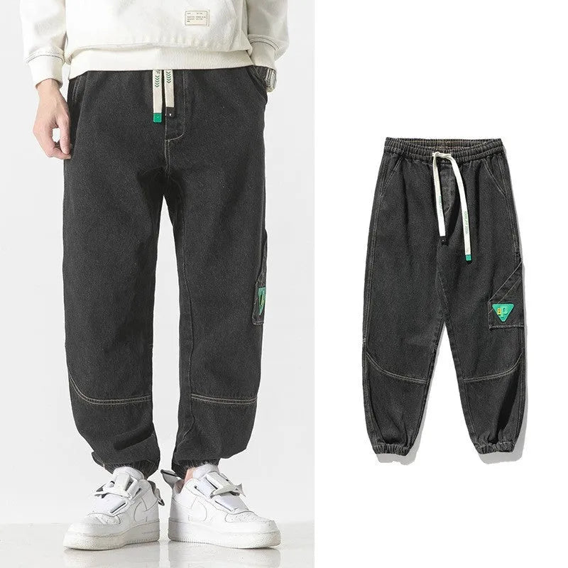 Men's loose-fit tapered cotton trousers in grey, showing the mid-waist and tapered leg cut.