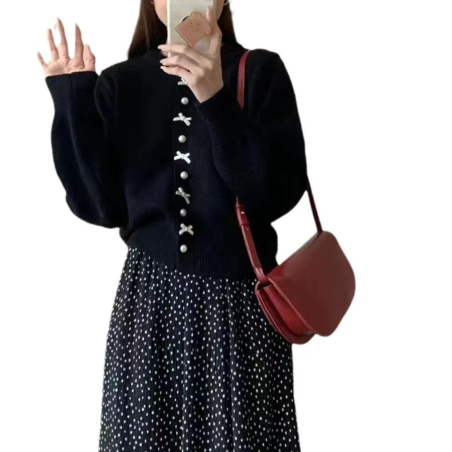 Women's cardigan sweater with a decorative bow and pearl buttons, shown in a solid colour.