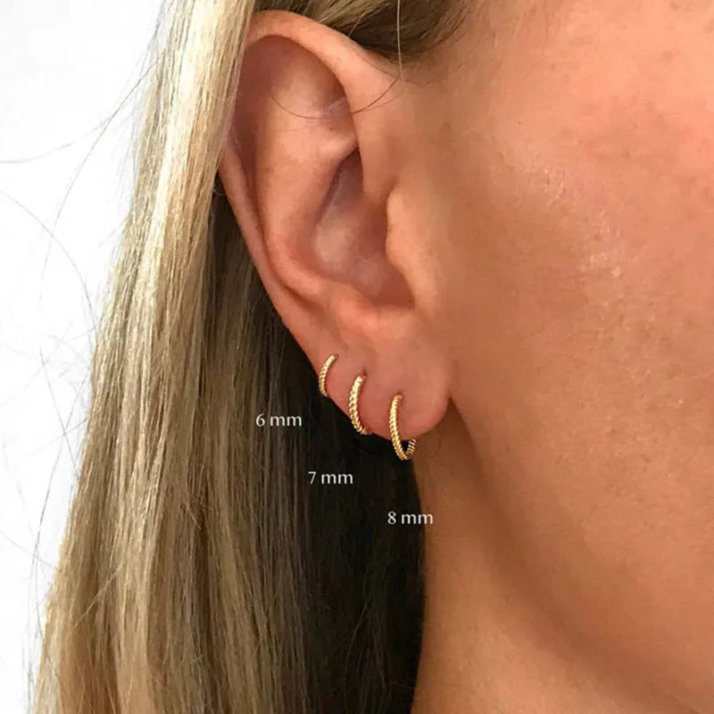 Close-up of a pair of twisted string round sterling silver earrings with gold plating.