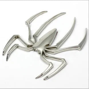 Three-dimensional metal spider bumper sticker in metallic finish on a car bumper.