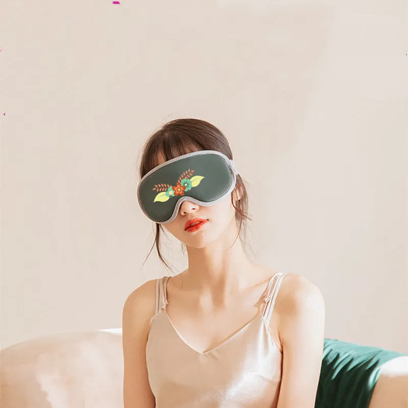 Pink and green portable USB-powered eye massage goggles with a suede shell on a grey background.