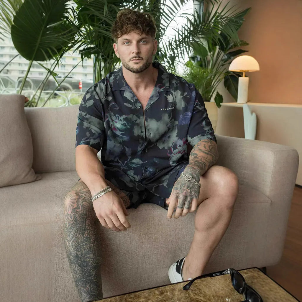 Man wearing a loose, light grey printed short sleeve casual top made from stretch polyester fabric.