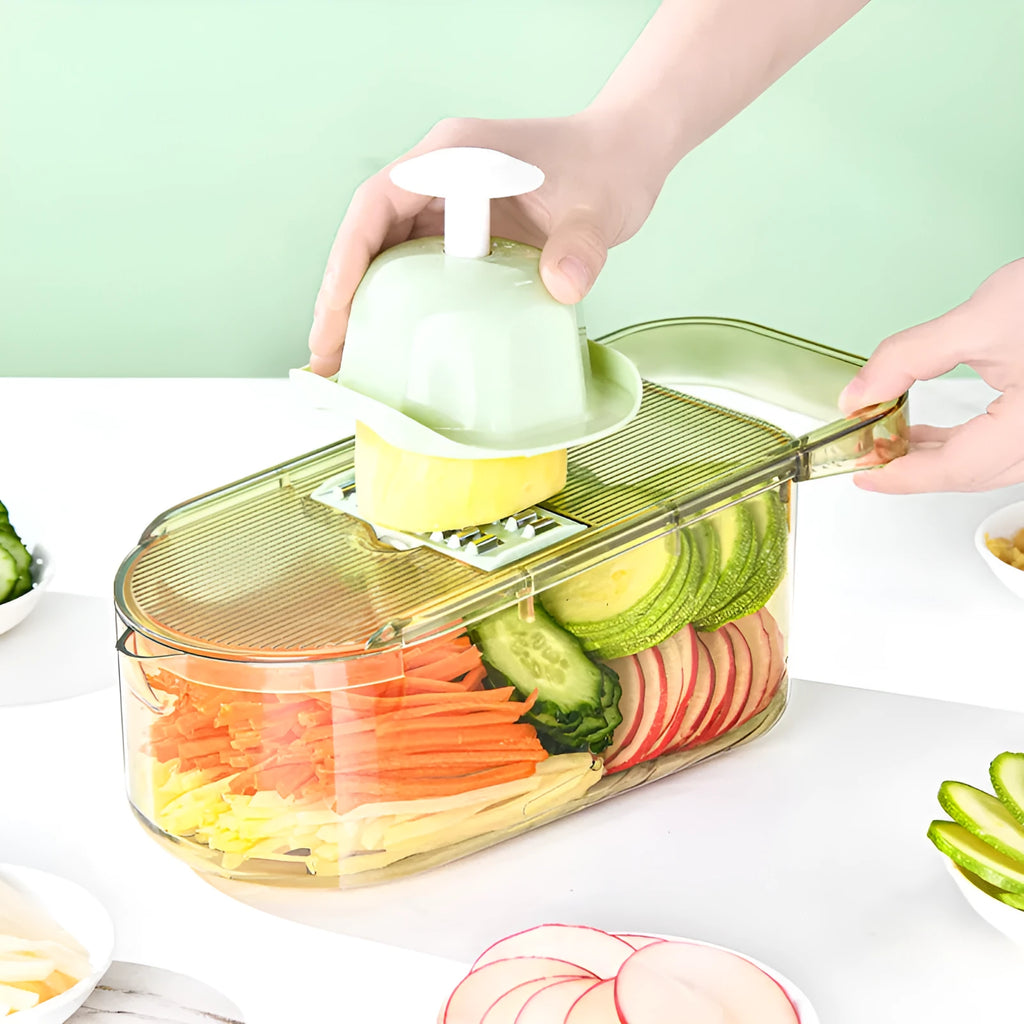 Transparent green vegetable chopper with multiple stainless steel blades and a hand protector on a kitchen worktop