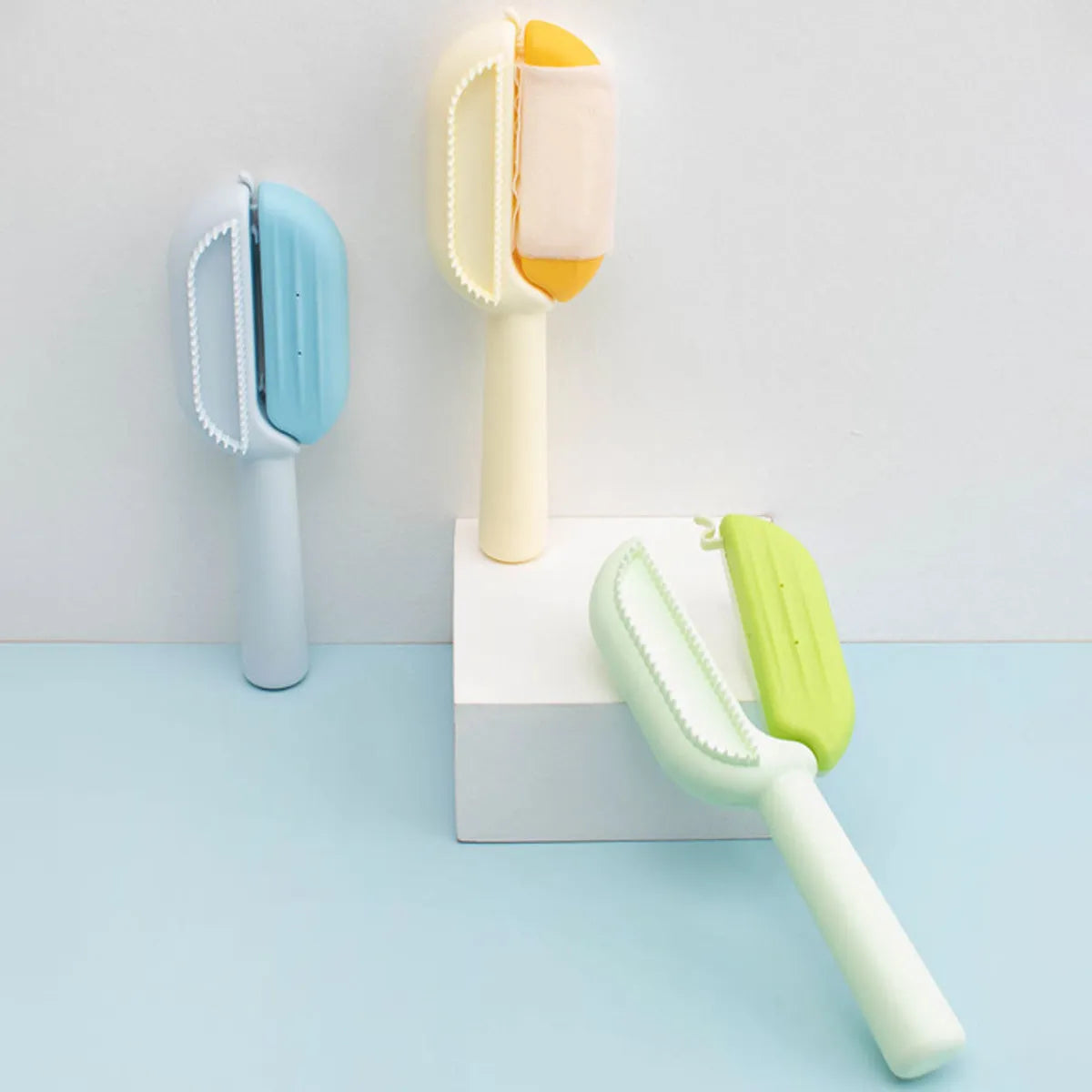 Blue pet grooming comb with integrated water tank and cleaning brush on a white background.