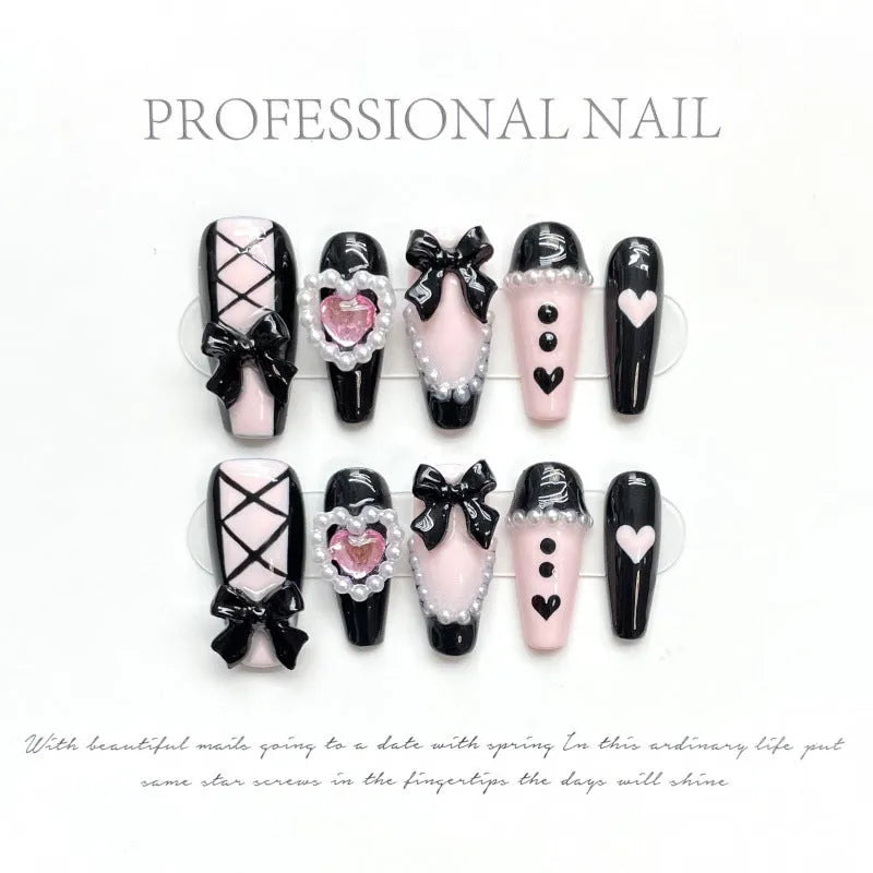 Black and pink heart-shaped handmade manicure set with bow pattern, shown in detachable plastic armour suit.