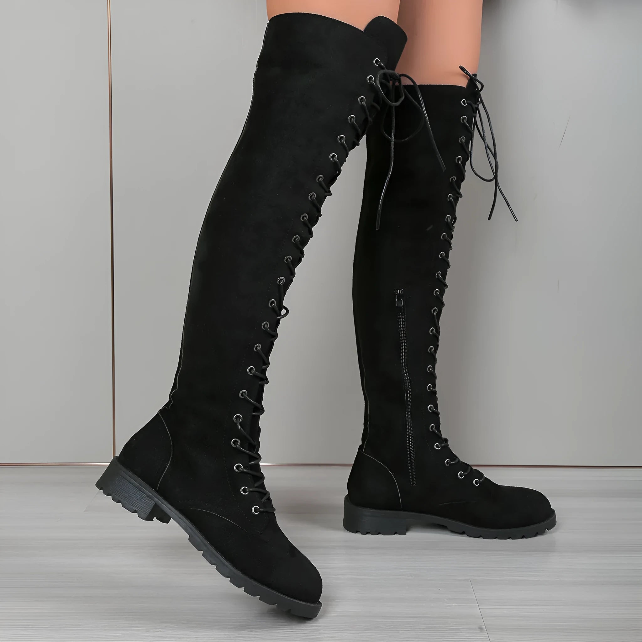 Black lace-up over-the-knee boots with round toe and flat rubber sole, showing stitching details on artificial PU upper