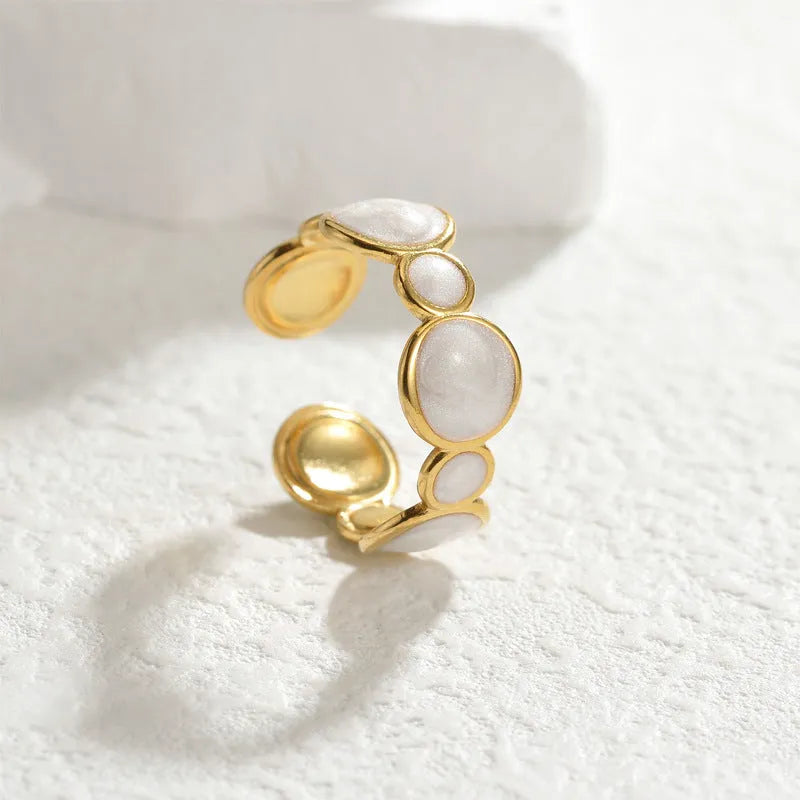 A stainless steel geometric ring with an adjustable opening on a plain background.