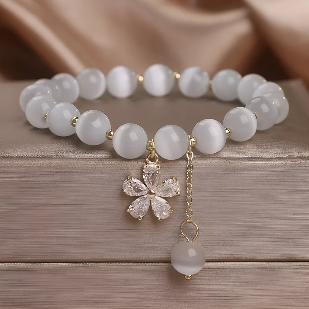 Women's white cat's eye crystal bracelet with flower decoration, tassel detail, and morganite safety buckle pendant