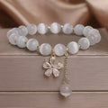 Women's white cat's eye crystal bracelet with flower decoration, tassel detail, and morganite safety buckle pendant
