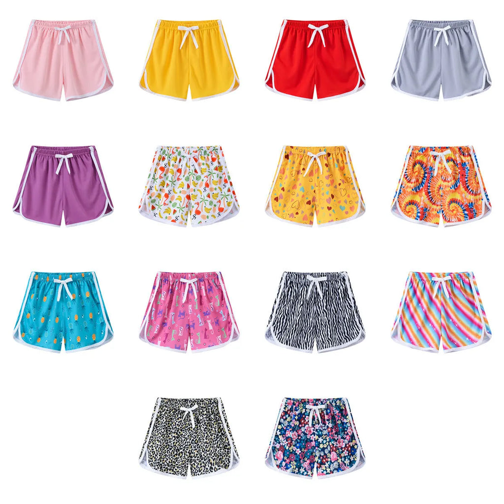Children's polyester beach shorts in multiple colours and prints including pineapple, kitten, and solid designs