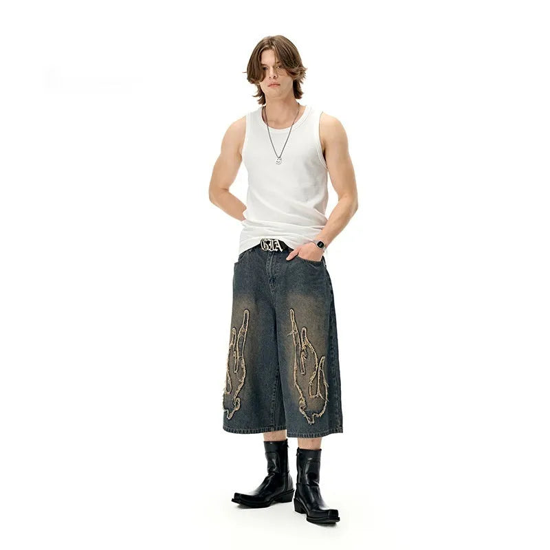 Men's black denim shorts with cropped length and flame embroidery patches on the leg.