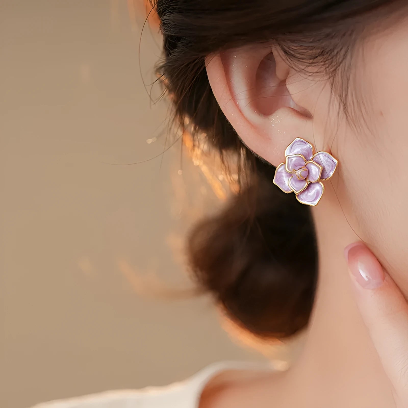 A pair of purple and gold floral stud earrings with detailed needlework and an oil-spot glaze finish.
