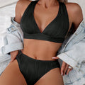 Women's halter strap split swimsuit bikini set in black with shorts and top on white background