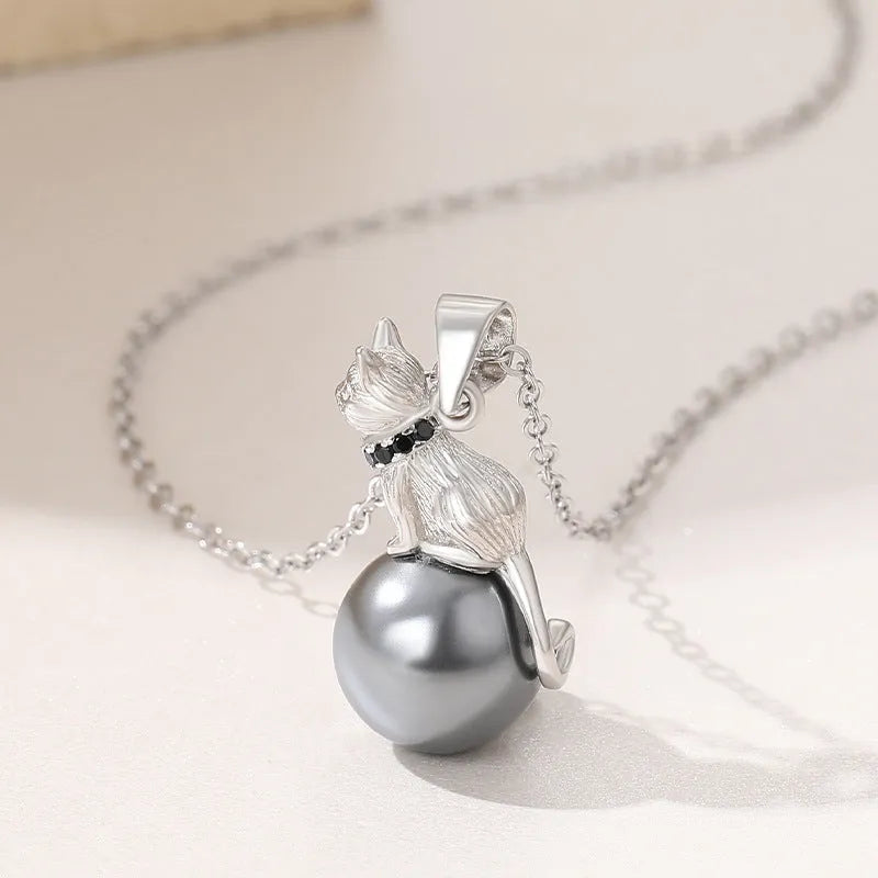Close-up of a sterling silver cat pendant on a delicate clavicle chain necklace.
