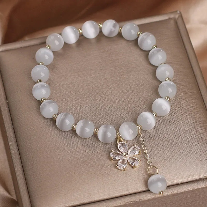 Women's white cat's eye crystal bracelet with flower decoration, tassel detail, and morganite safety buckle pendant