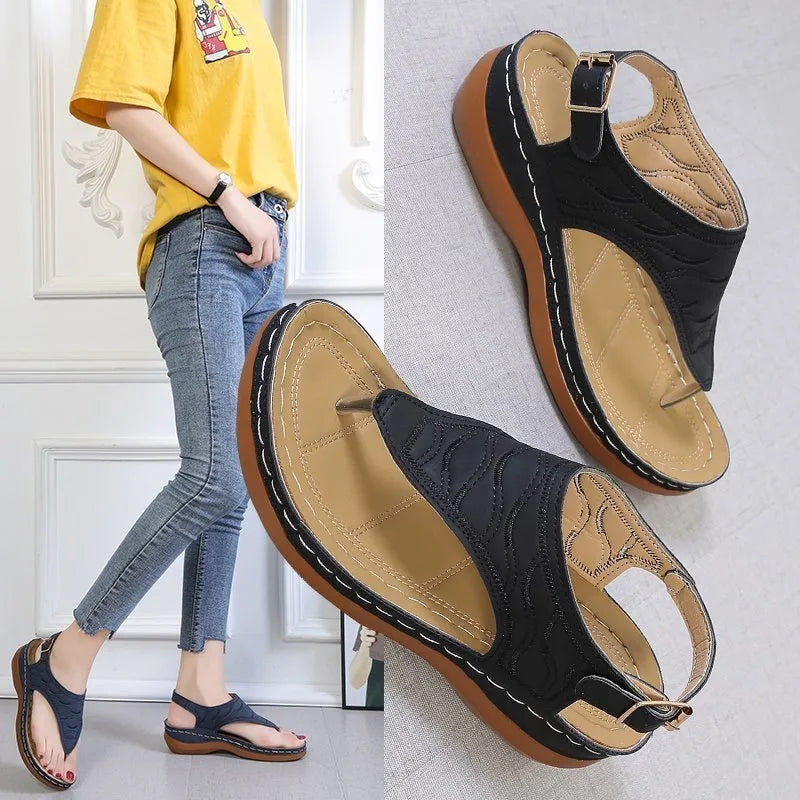 Women's black wedge heel sandals with an adjustable buckle strap on a light background.