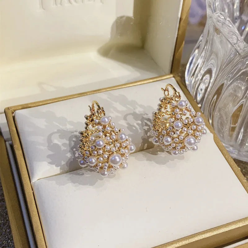 Gold-coloured copper flower basket earrings with white pearl inlay and small rice-shaped bead details.