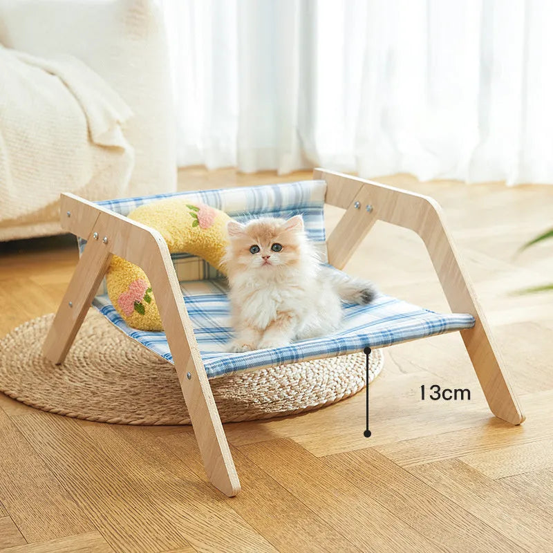 Elevated wooden cat bed with blue cloth hammock surface on a wooden floor