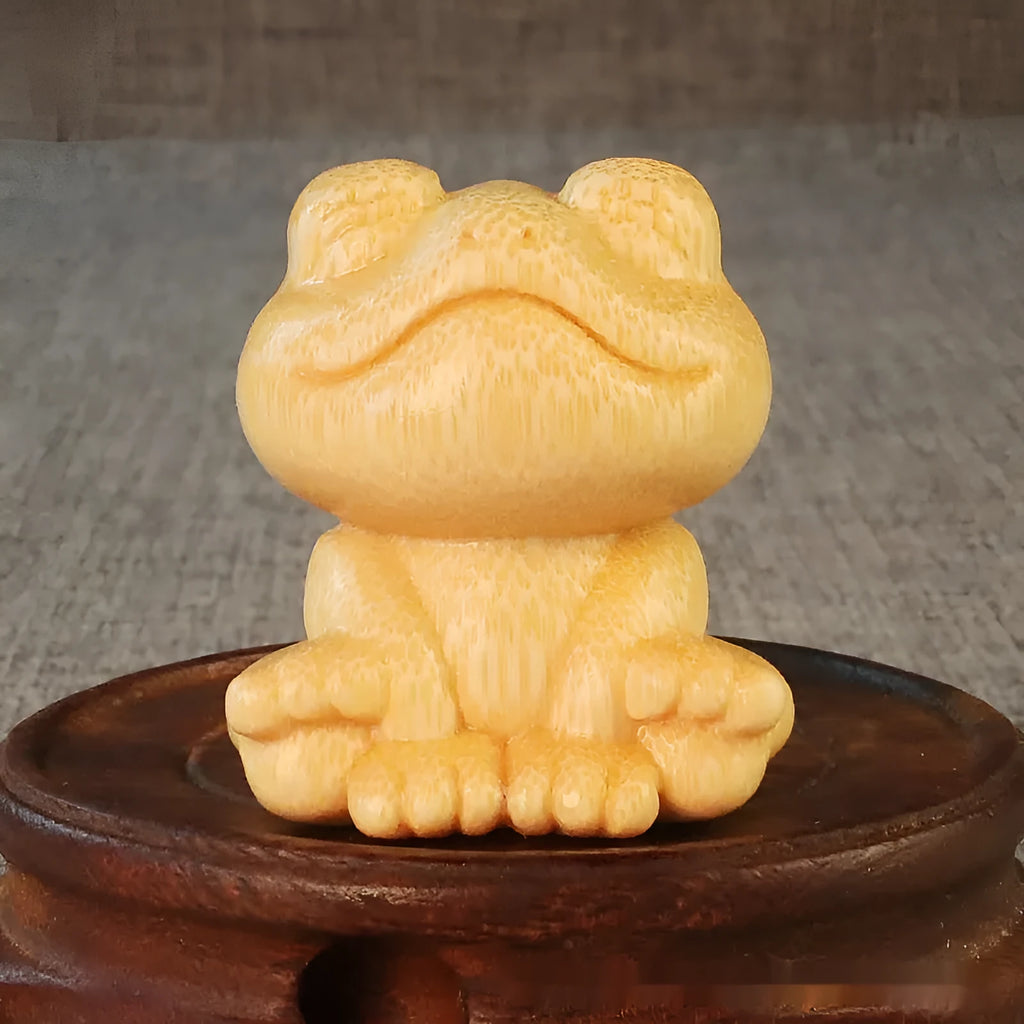 Solid bamboo smiling frog carving ornament with cartoon style on a wooden surface.