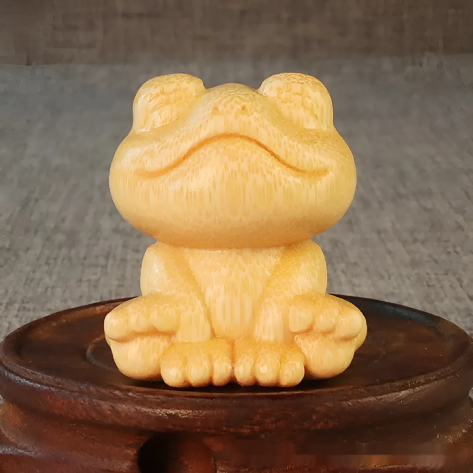 Solid bamboo smiling frog carving ornament with cartoon style on a wooden surface.